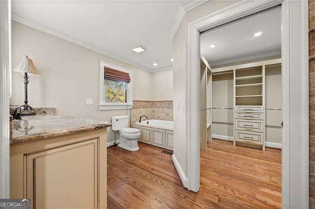 bathroom with a bath, vanity, hardwood / wood-style flooring, and ornamental molding