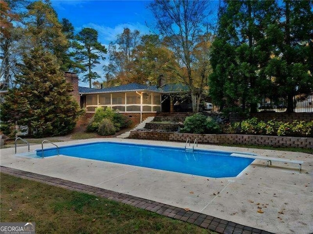 view of swimming pool with a patio, a diving board, and a sunroom