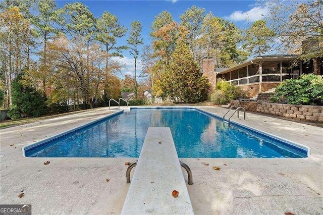 view of swimming pool with a patio area and a diving board