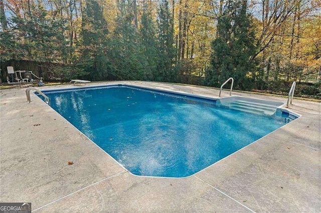 view of swimming pool featuring a diving board and a patio