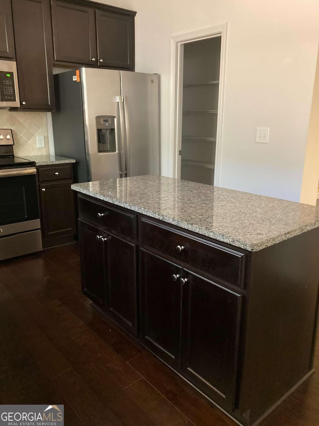 kitchen with decorative backsplash, dark brown cabinetry, dark wood-type flooring, and appliances with stainless steel finishes