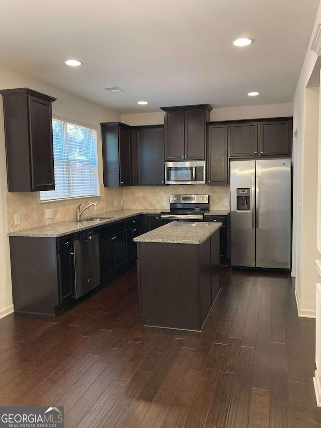 kitchen with a center island, sink, dark hardwood / wood-style floors, appliances with stainless steel finishes, and tasteful backsplash