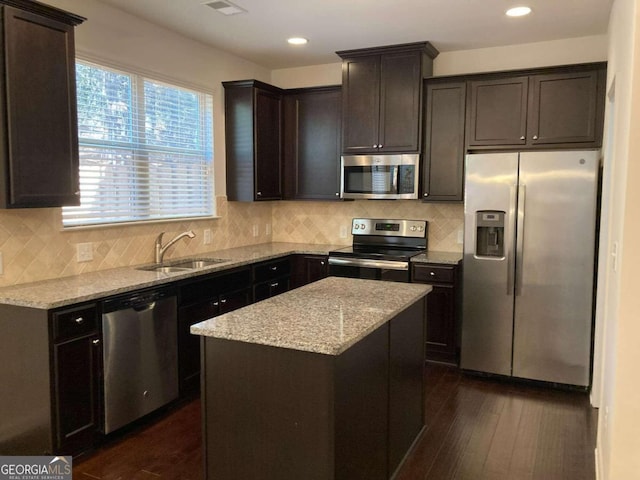 kitchen featuring light stone countertops, sink, stainless steel appliances, dark hardwood / wood-style floors, and a kitchen island