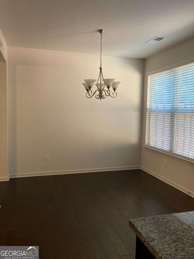 unfurnished dining area featuring dark hardwood / wood-style flooring and a notable chandelier