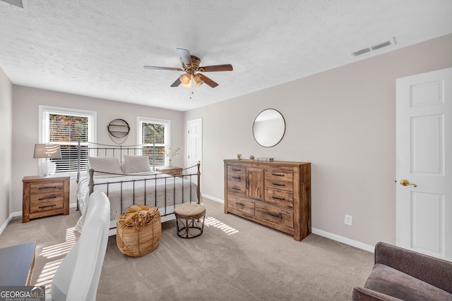 bedroom featuring ceiling fan, light carpet, and a textured ceiling