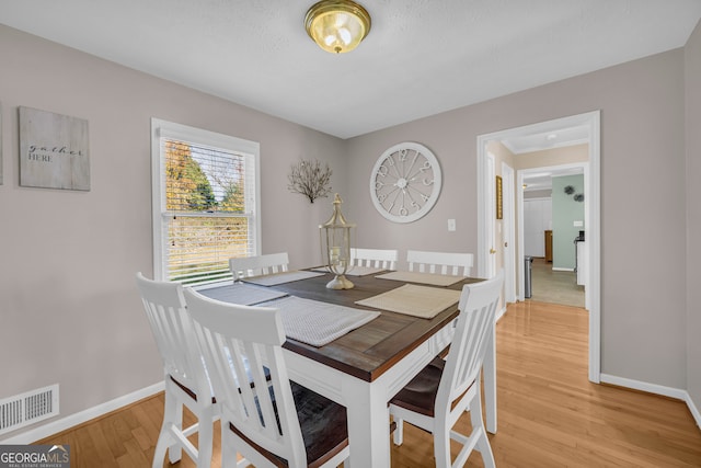 dining space with light hardwood / wood-style flooring and a textured ceiling