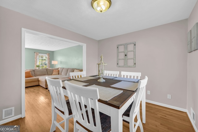 dining space featuring hardwood / wood-style floors and a textured ceiling