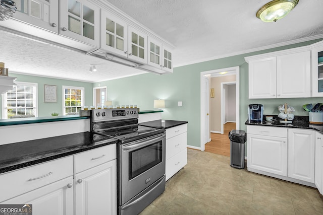 kitchen featuring a textured ceiling, stainless steel electric range oven, crown molding, light tile patterned floors, and white cabinetry