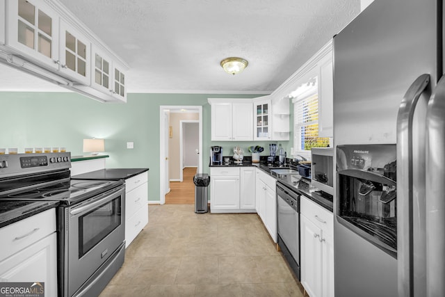 kitchen with white cabinets, crown molding, a textured ceiling, and appliances with stainless steel finishes