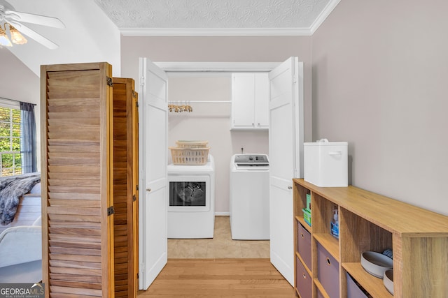 laundry room featuring cabinets, light hardwood / wood-style floors, a textured ceiling, and independent washer and dryer