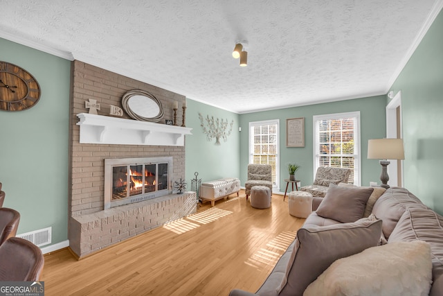 living room featuring hardwood / wood-style floors, a fireplace, crown molding, and a textured ceiling