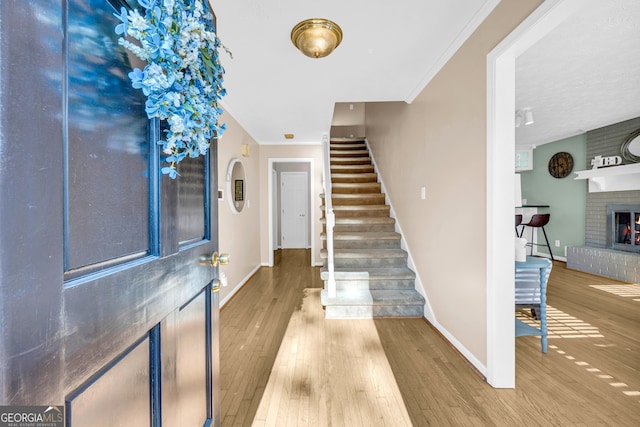 entrance foyer featuring hardwood / wood-style floors, ornamental molding, and a fireplace