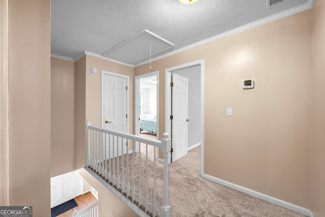 hall with a textured ceiling, crown molding, and light carpet