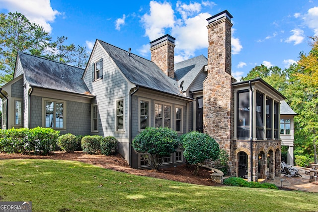 rear view of house featuring a lawn and a sunroom