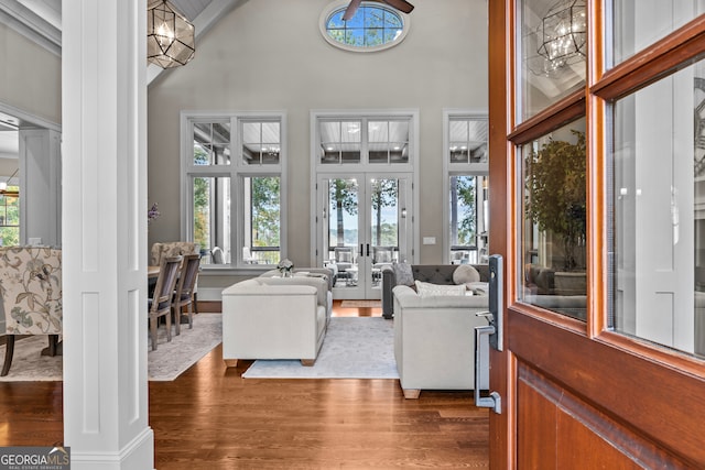 living room featuring a high ceiling, an inviting chandelier, french doors, dark hardwood / wood-style floors, and ornate columns