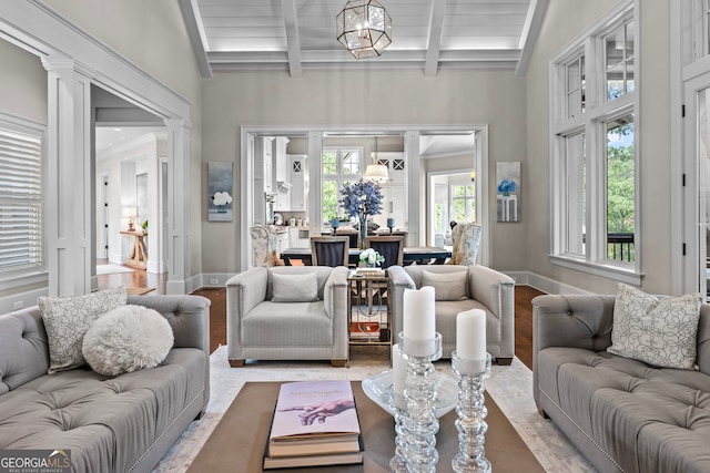 living room featuring beam ceiling, a wealth of natural light, a notable chandelier, and hardwood / wood-style floors