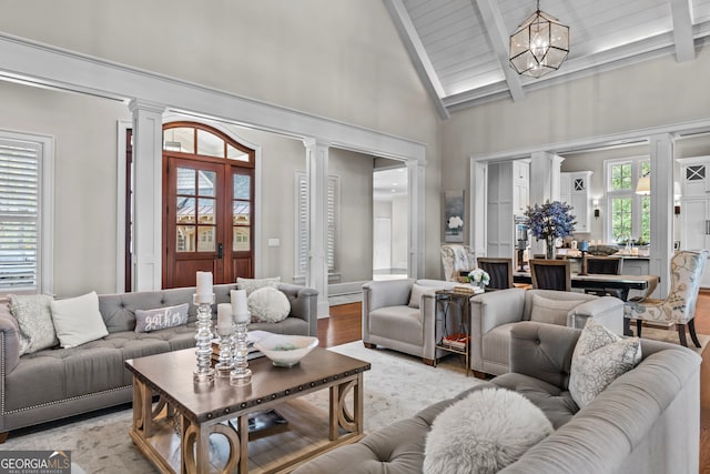 living room featuring beamed ceiling, plenty of natural light, high vaulted ceiling, and a chandelier