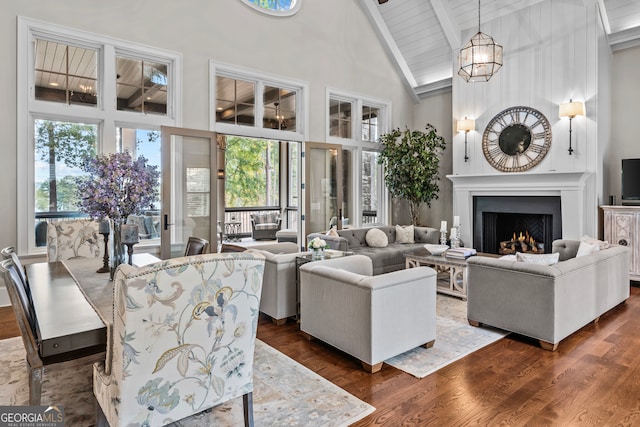 living room with dark wood-type flooring, beam ceiling, high vaulted ceiling, wooden ceiling, and a notable chandelier