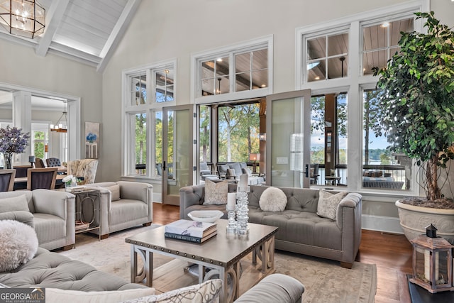 living room featuring hardwood / wood-style floors, high vaulted ceiling, a notable chandelier, and beam ceiling