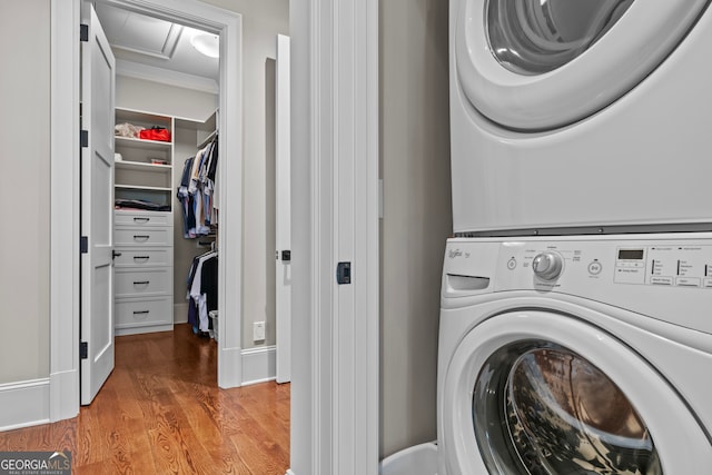 laundry room with wood-type flooring and stacked washer / dryer