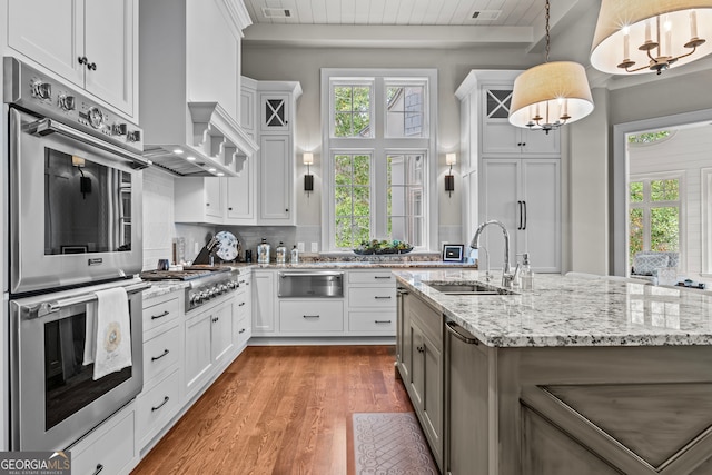 kitchen featuring pendant lighting, light wood-type flooring, white cabinetry, and sink