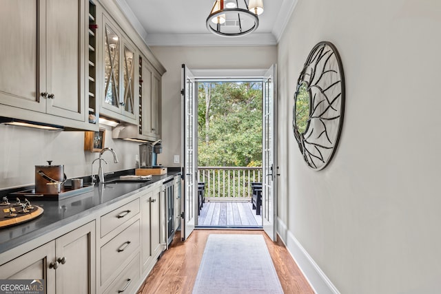 entryway with sink, light wood-type flooring, ornamental molding, and beverage cooler