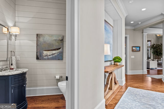 bathroom with hardwood / wood-style floors, vanity, toilet, and ornamental molding