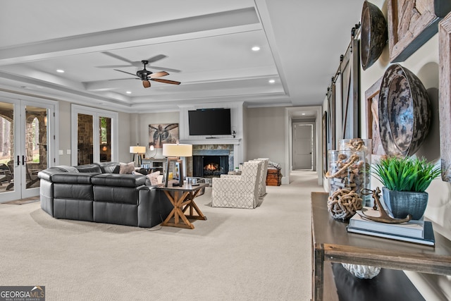 living room with ceiling fan, light colored carpet, french doors, and a tray ceiling