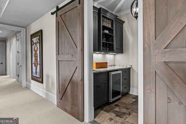 bar featuring a barn door, light stone countertops, wine cooler, and dark carpet