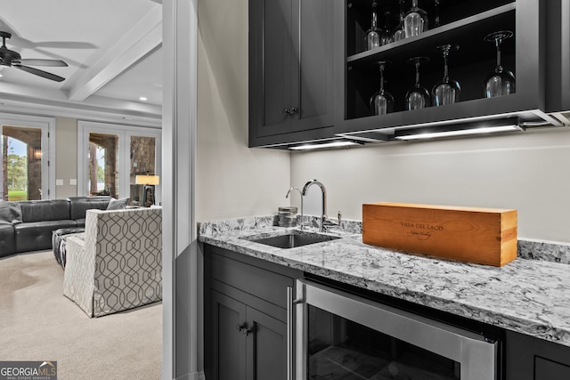 kitchen featuring carpet, light stone counters, sink, beamed ceiling, and wine cooler