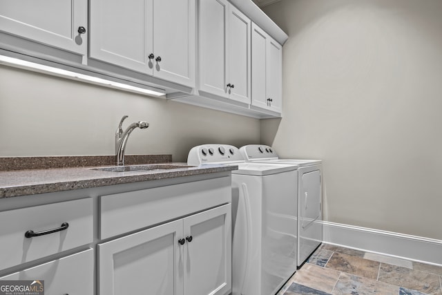 clothes washing area featuring washer and clothes dryer, sink, and cabinets