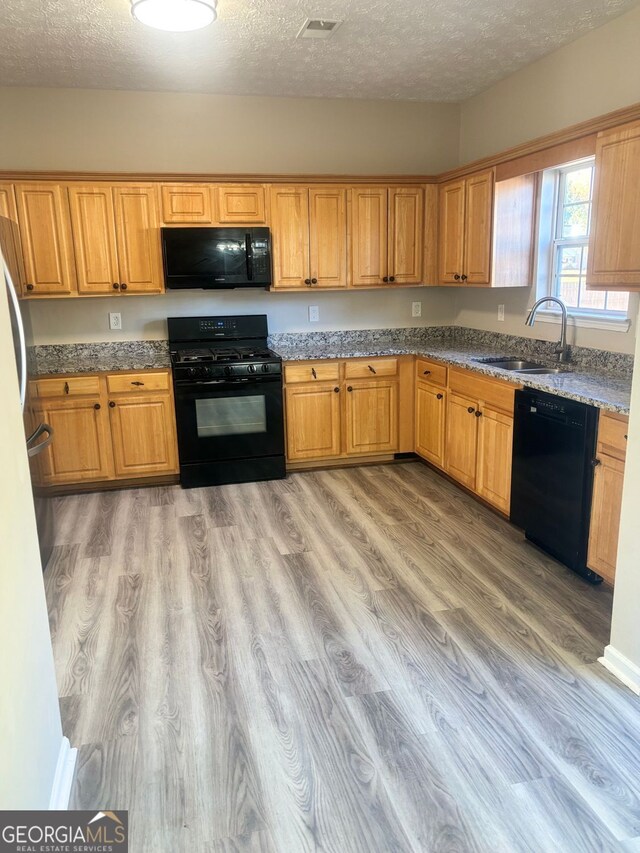 kitchen with light hardwood / wood-style floors, sink, a textured ceiling, and black appliances