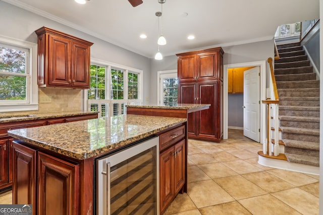 kitchen featuring decorative light fixtures, a kitchen island, beverage cooler, and ornamental molding