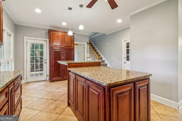 kitchen with pendant lighting, light stone countertops, ornamental molding, light tile patterned floors, and a kitchen island