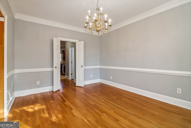 unfurnished room with wood-type flooring, ornamental molding, and a chandelier