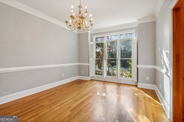 empty room featuring ornamental molding, a chandelier, and light wood-type flooring