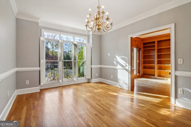 unfurnished room with crown molding, a chandelier, and hardwood / wood-style flooring