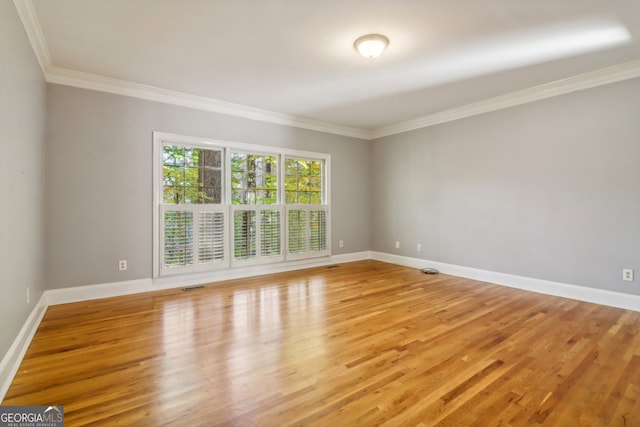 spare room featuring light wood-type flooring and ornamental molding