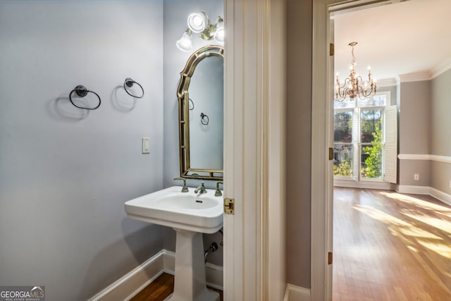 bathroom with hardwood / wood-style floors, ornamental molding, and a notable chandelier