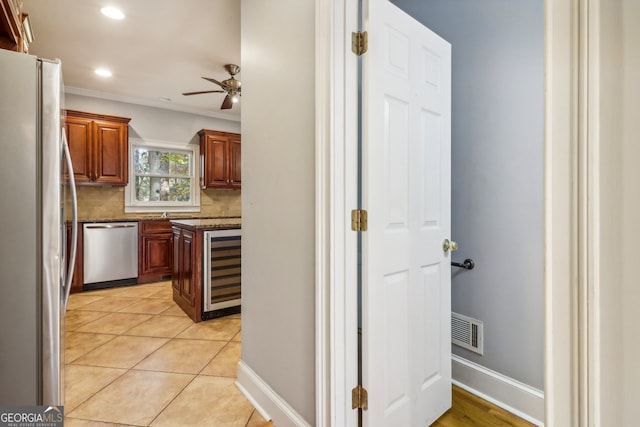 kitchen featuring appliances with stainless steel finishes, tasteful backsplash, beverage cooler, crown molding, and ceiling fan