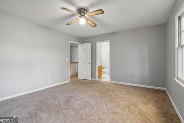 unfurnished bedroom with ceiling fan, light colored carpet, and ensuite bathroom