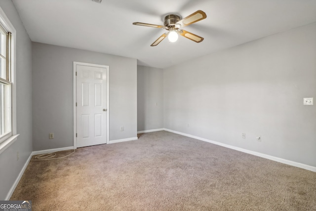 empty room featuring carpet flooring, a wealth of natural light, and ceiling fan