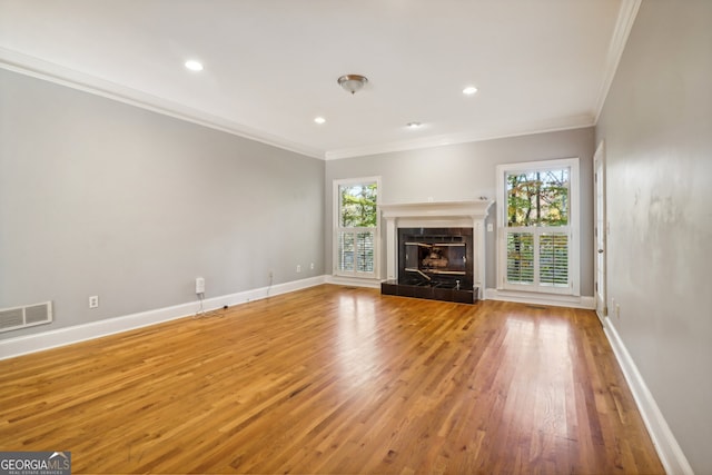 unfurnished living room featuring a tile fireplace, crown molding, and hardwood / wood-style flooring