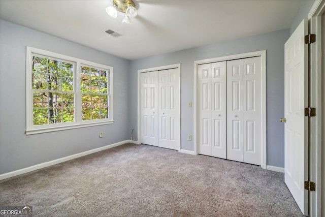 unfurnished bedroom featuring carpet floors and multiple closets