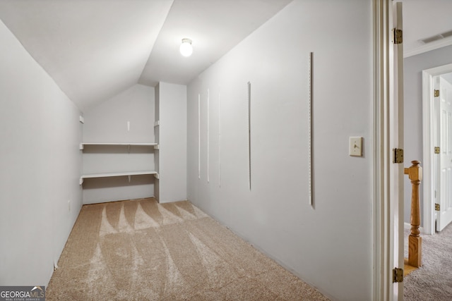 walk in closet with light carpet and vaulted ceiling