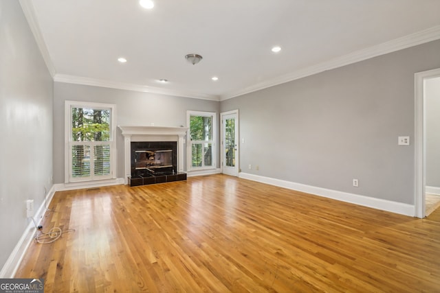 unfurnished living room featuring light hardwood / wood-style floors, crown molding, and a tile fireplace