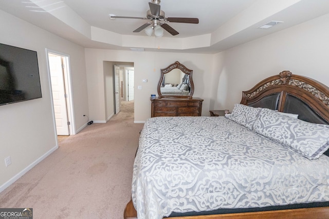 carpeted bedroom featuring ceiling fan and a raised ceiling