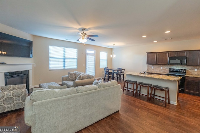 living room with dark hardwood / wood-style flooring, ceiling fan, and sink