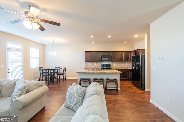 living room with dark hardwood / wood-style floors, sink, and ceiling fan with notable chandelier