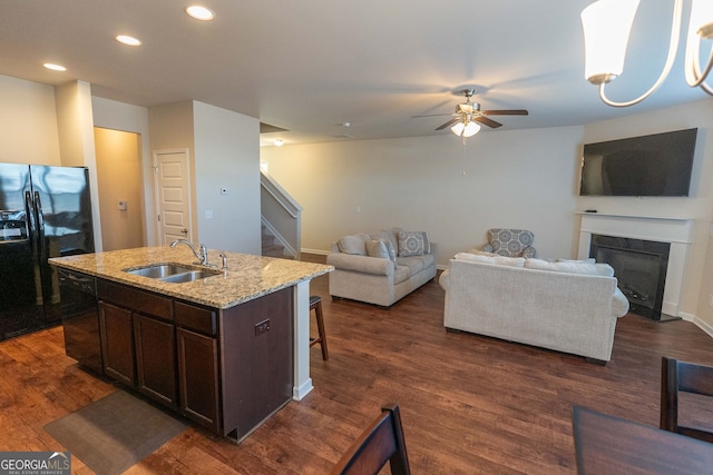 kitchen featuring dark brown cabinetry, ceiling fan, sink, a kitchen island with sink, and black appliances